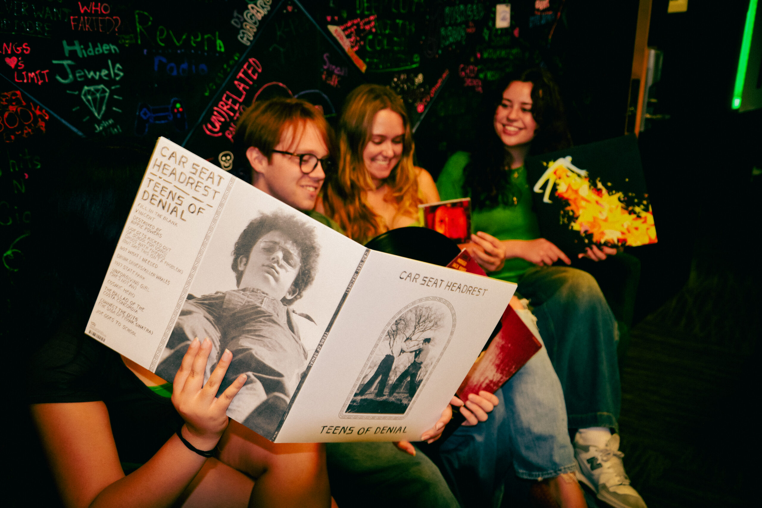 Four DJs in the Station Production Studio, sitting on our green couch ad comparing albums